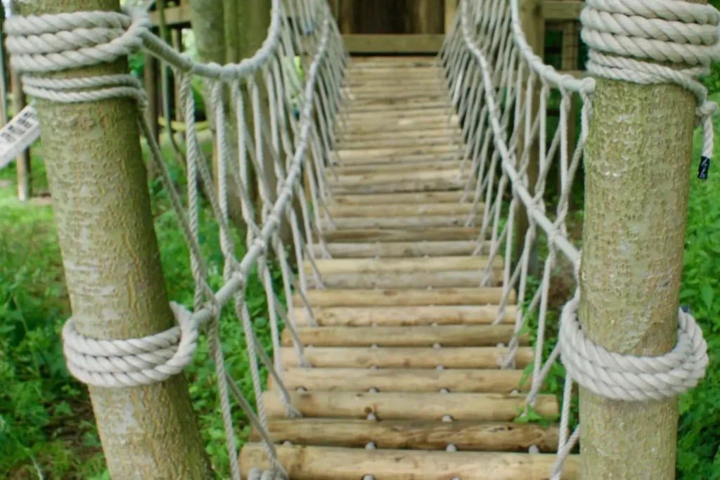Log-Rope-Bridge-by-Treehouse-Life-Ltd-attached-to-trees-in-woodland