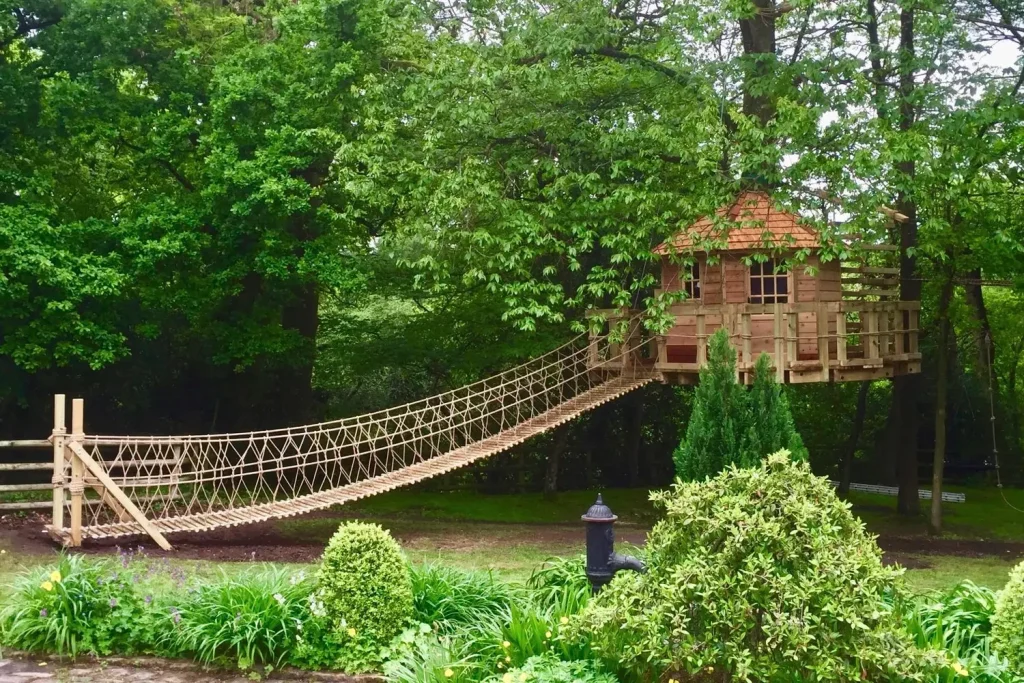 Family garden Treehouse suspended around a tree with a long Rope Ladder entrance from the lawn