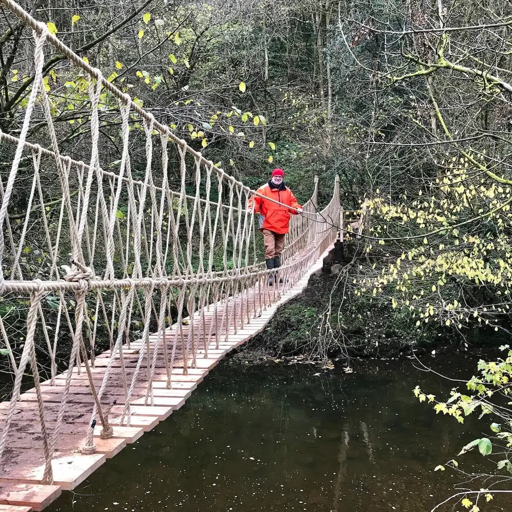 Man standing on a Rope Bridge above a river