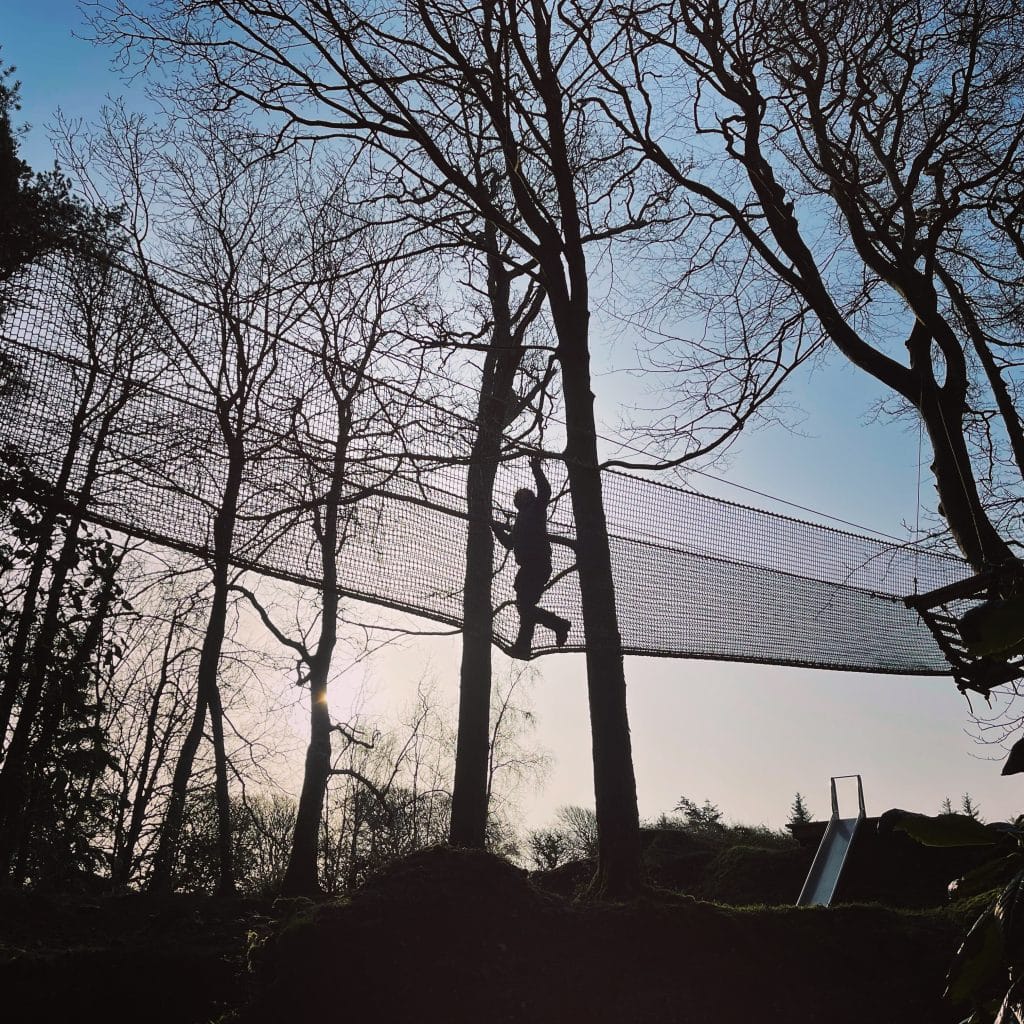 A man crosses a high rope bridge at Muncaster Castle in the Lake District.